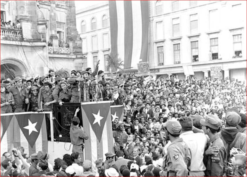 A black and white photograph of Fidel Castro giving a speech to a large crowd in 1959.
